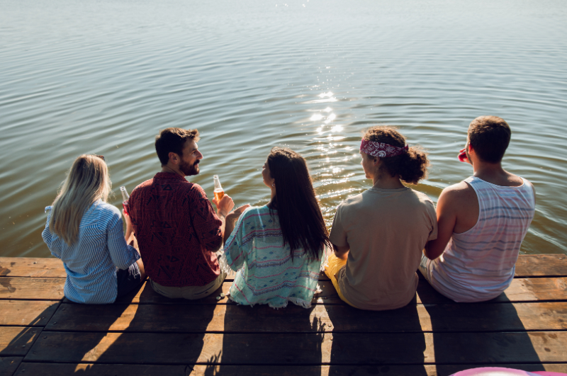 group of friends sitting on the edge of pier